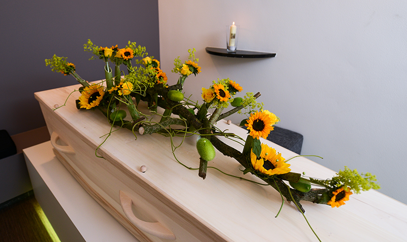 Kamer met een houten uitvaartkist met zonnebloemen